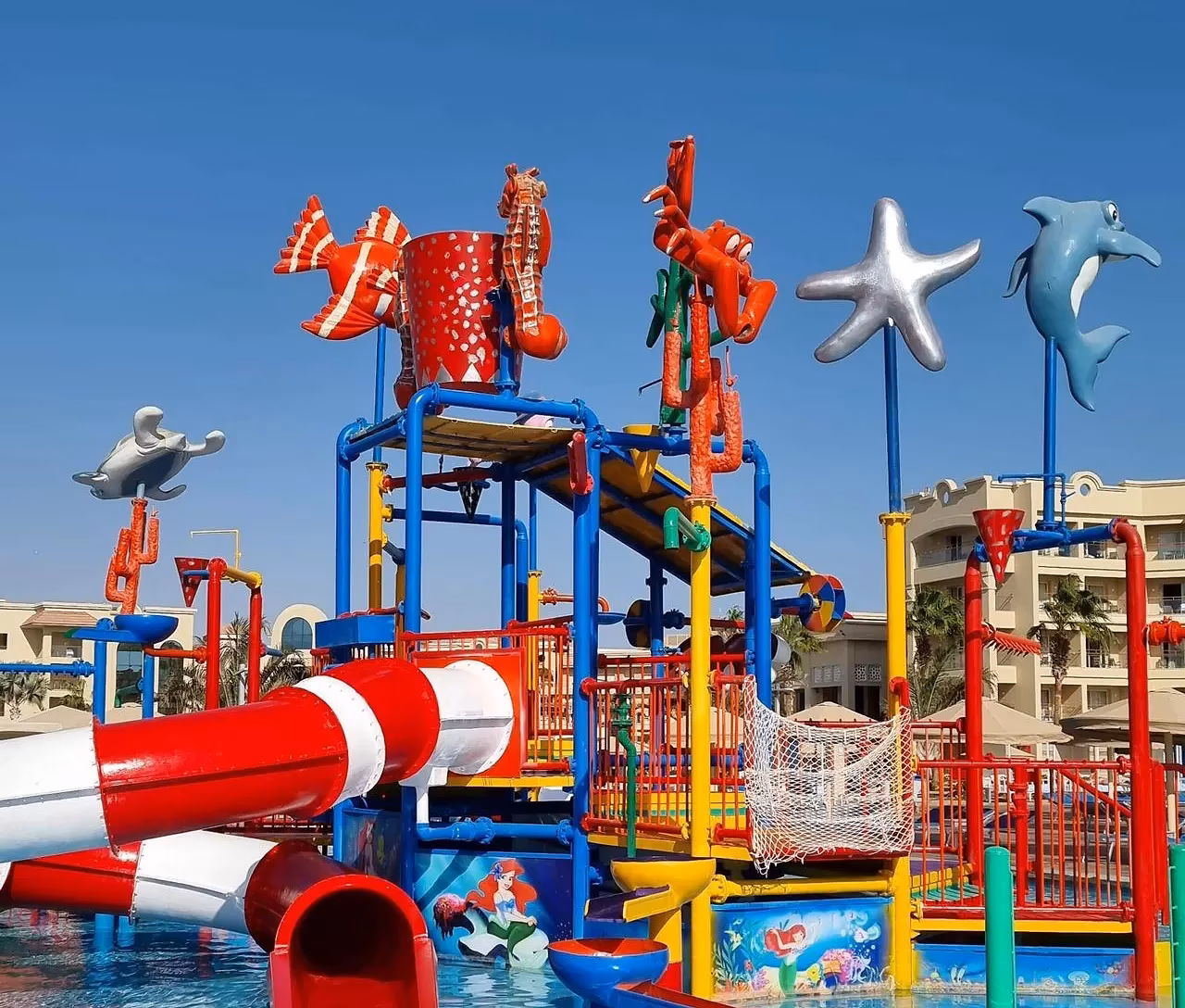 Een kinderspeelstructuur met rode en gele glijbanen in een zwembad