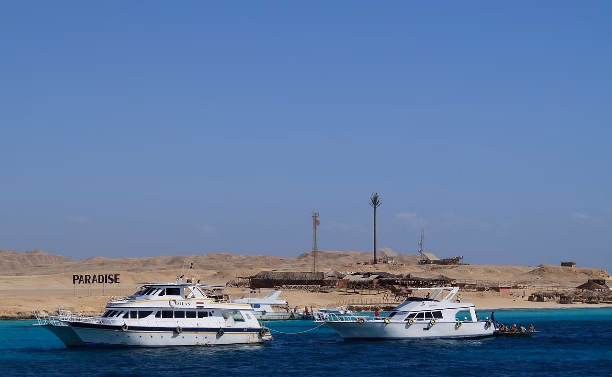 Excursieboten bij een eiland met strandhutten voor de kust van Hurghada