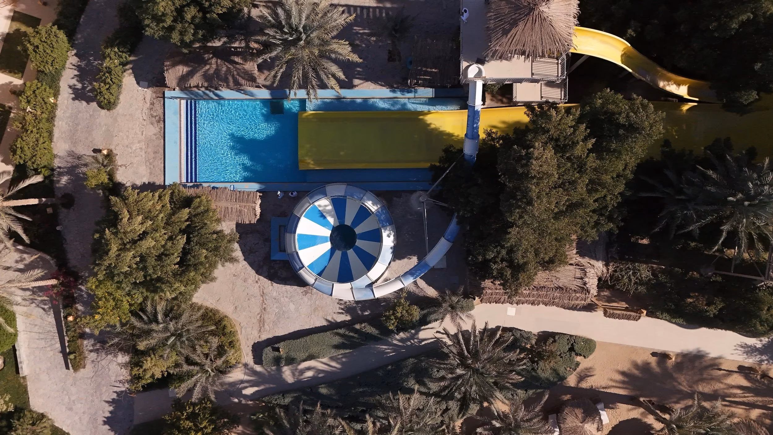 Luchtfoto recht van boven op de glijbanen, de komglijbaan en een zwembad in het aquapark van Hotel Sindbad Club in Hurghada