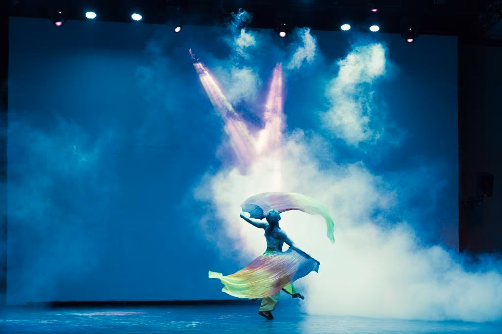 Een danseres met kleurige sluiers op een podium in rook en spotlicht tijdens een avondshow in Sindbad Club in Hurghada