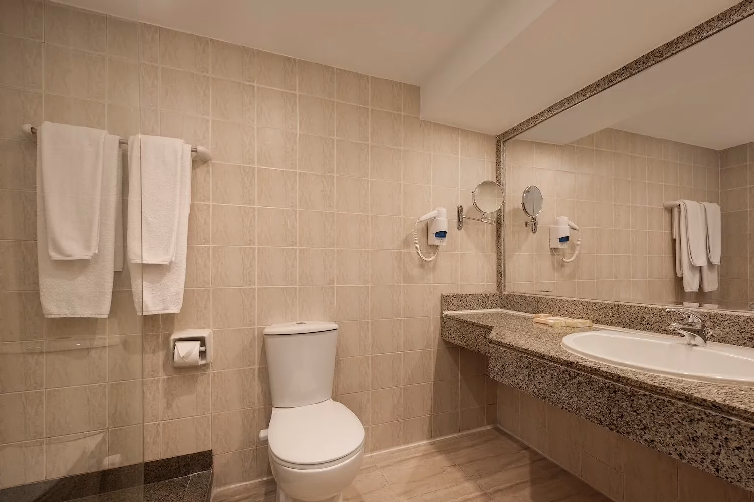 Badkamer met beige tegels, granieten wastafel en föhn in Hotel Sindbad Club in Hurghada