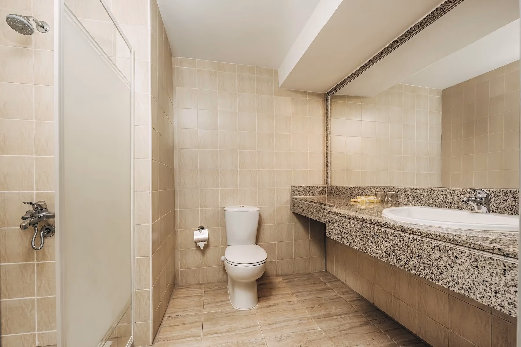 Badkamer met douche, beige tegels en granieten wastafelblad in Hotel Sindbad Club in Hurghada