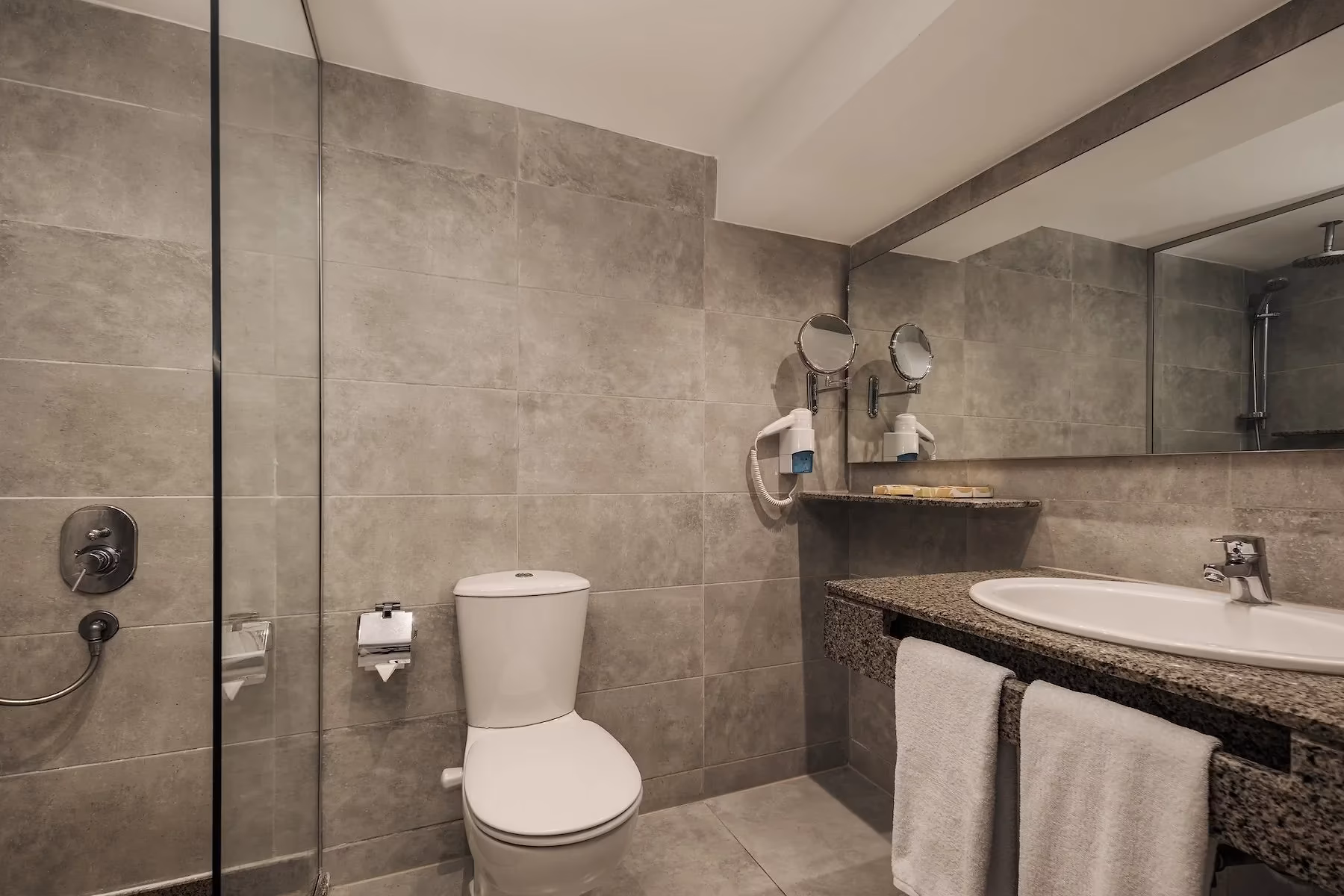 Badkamer met grijze tegels, glazen douchewand en scheerspiegel in Hotel Sindbad Club in Hurghada