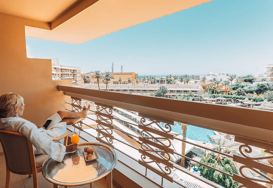 Uitzicht vanaf een balkon van Sindbad Club over het zwembad, de tuin en de stad Hurghada met de zee in de verte