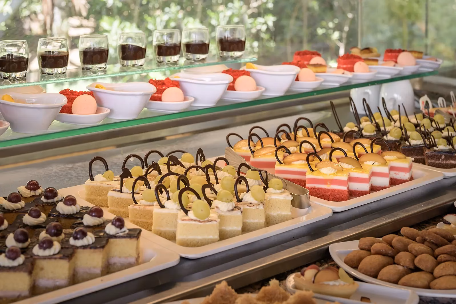 Dessertbuffet met rijen gebakjes, taartjes, koekjes en glaasjes pudding in Sindbad Club in Hurghada
