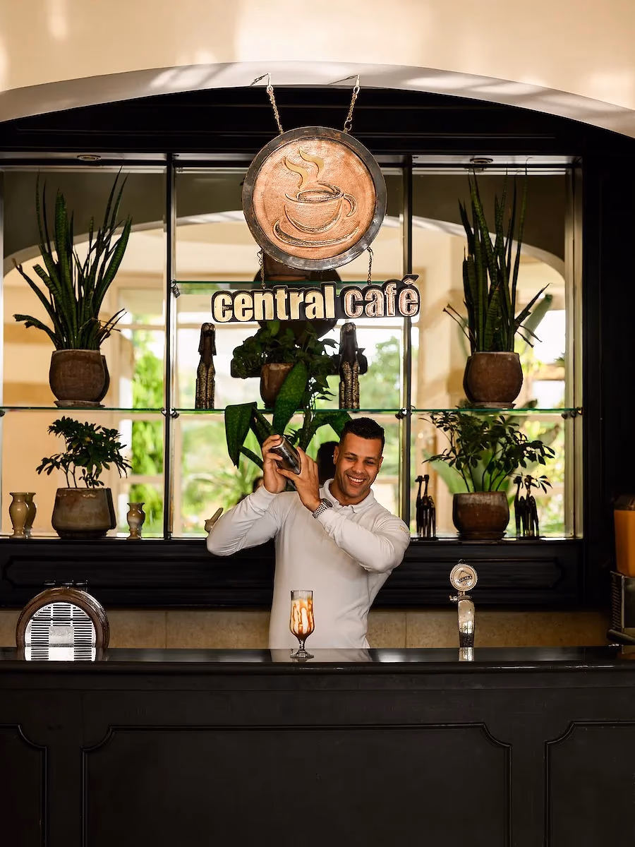 Barman achter de bar van Central Café met het naambord erboven in Hotel Sindbad Club in Hurghada