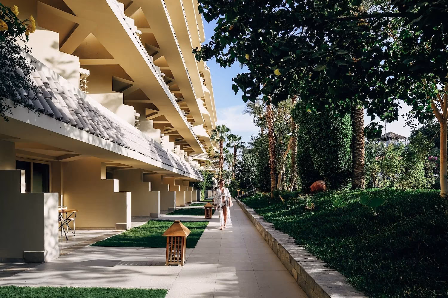 Rij terrassen op de begane grond langs een tuinpad met palmen bij Hotel Sindbad Club in Hurghada