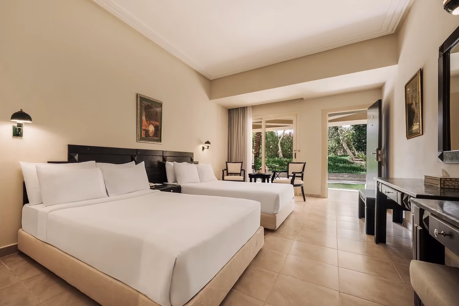 Deluxe familiekamer met tweepersoonsbed, eenpersoonsbed en open deur naar de tuin in Hotel Sindbad Club in Hurghada