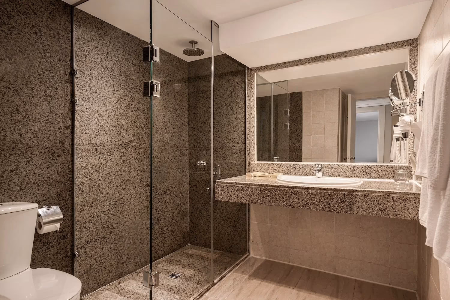 Badkamer met inloopdouche achter glas en granieten wastafel in de Deluxe familiesuite van Hotel Sindbad Club in Hurghada