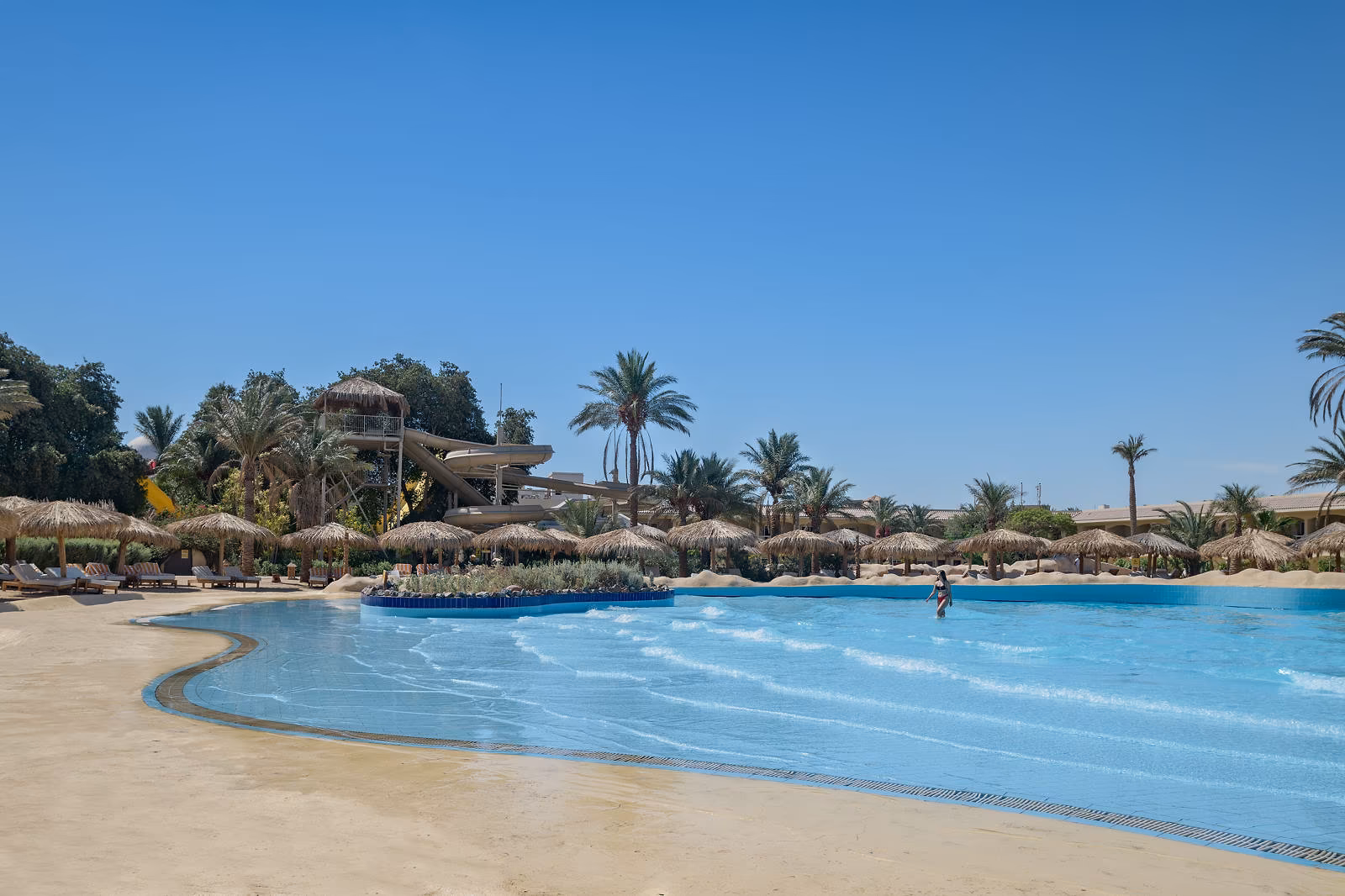 Het golfslagbad met zandstrandinstap en de glijbaantoren op de achtergrond bij Hotel Sindbad Club in Hurghada