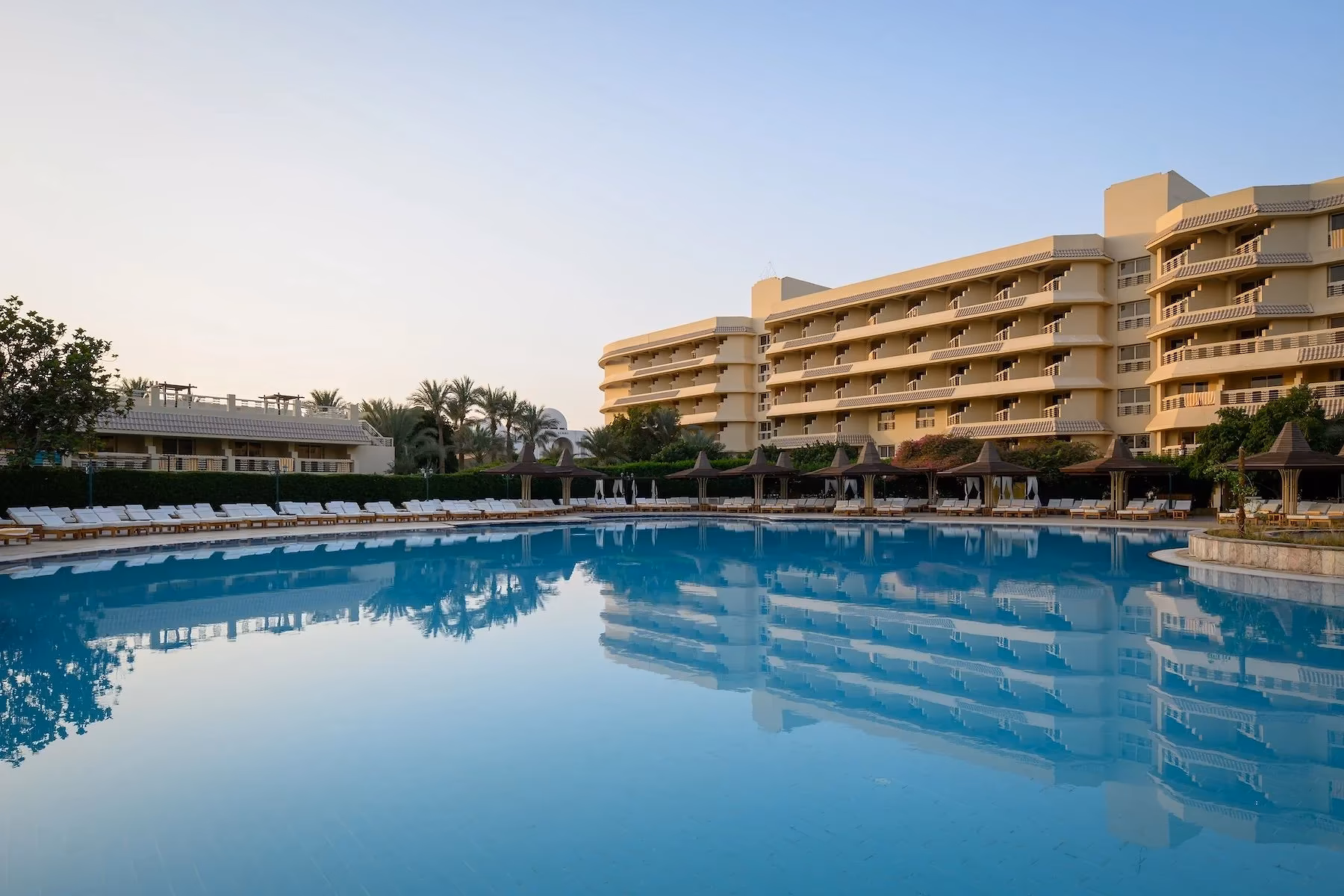 Het hoofdzwembad in de ochtend met de weerspiegeling van het hotelgebouw van Hotel Sindbad Club in Hurghada