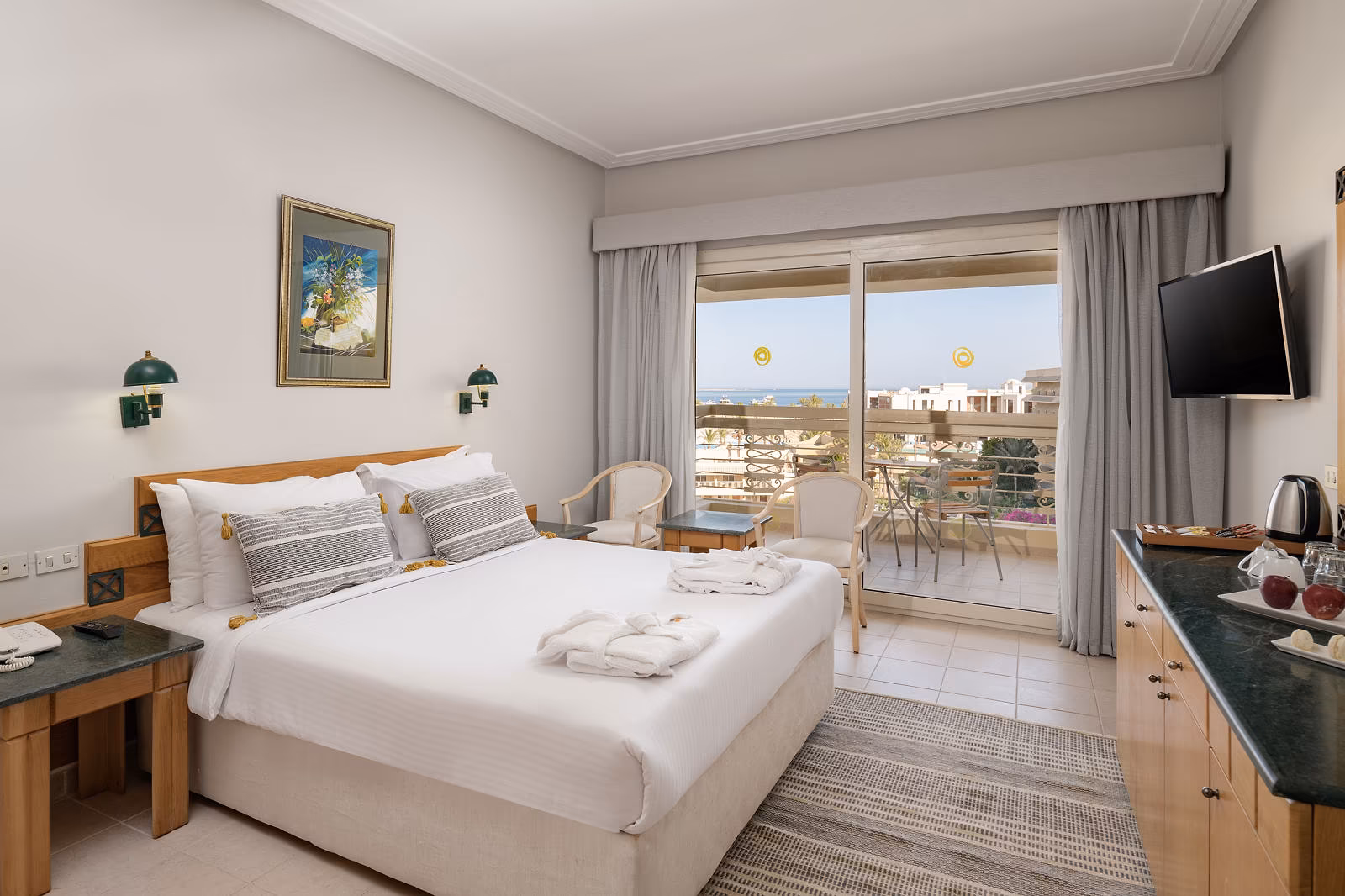 Kamer met tweepersoonsbed, houten meubels en balkon met zicht op de zee in de verte in Hotel Sindbad Club in Hurghada