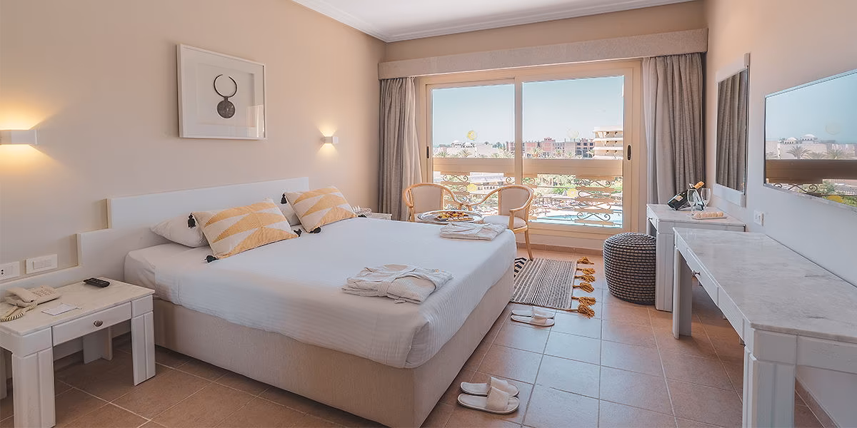 Tweepersoonskamer met een balkon met twee stoelen en zicht op het zwembad in Sindbad Club in Hurghada
