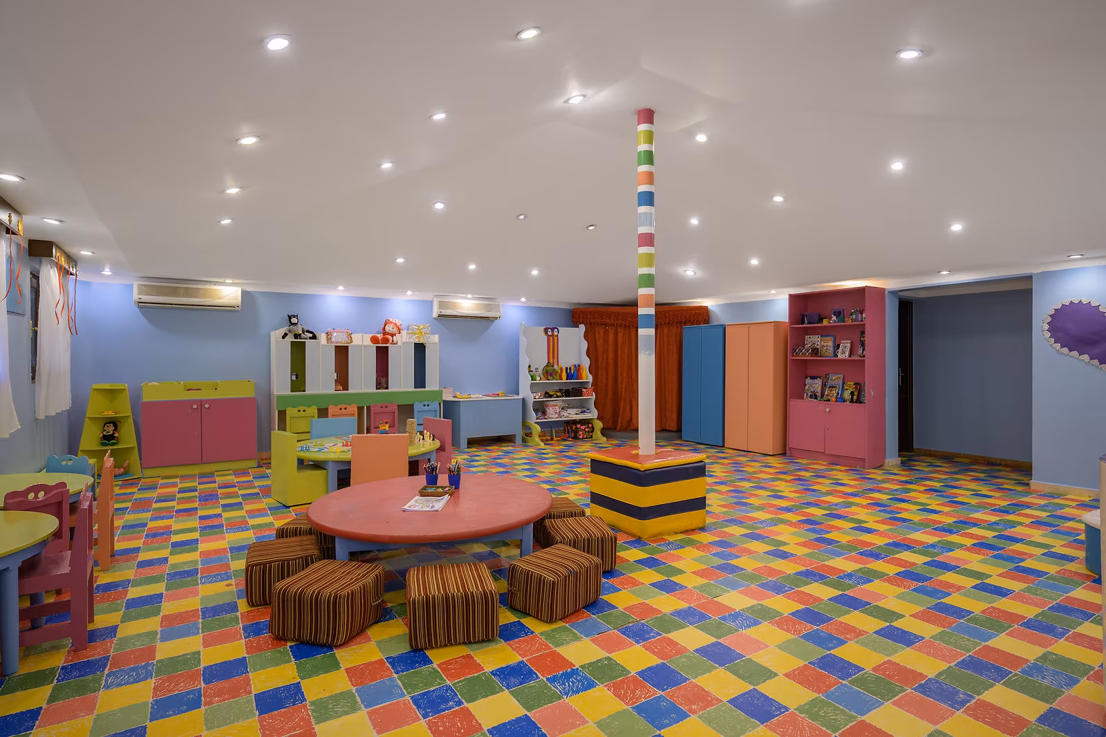 Binnenruimte van de kidsclub met gekleurde vloer, tafels en speelkasten in Hotel Sindbad Club in Hurghada