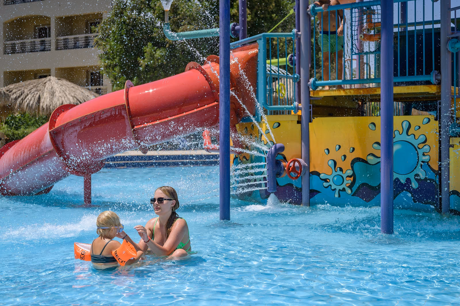 Moeder en kind in het kinderbad bij de rode glijbaan en waterstralen van Hotel Sindbad Club in Hurghada