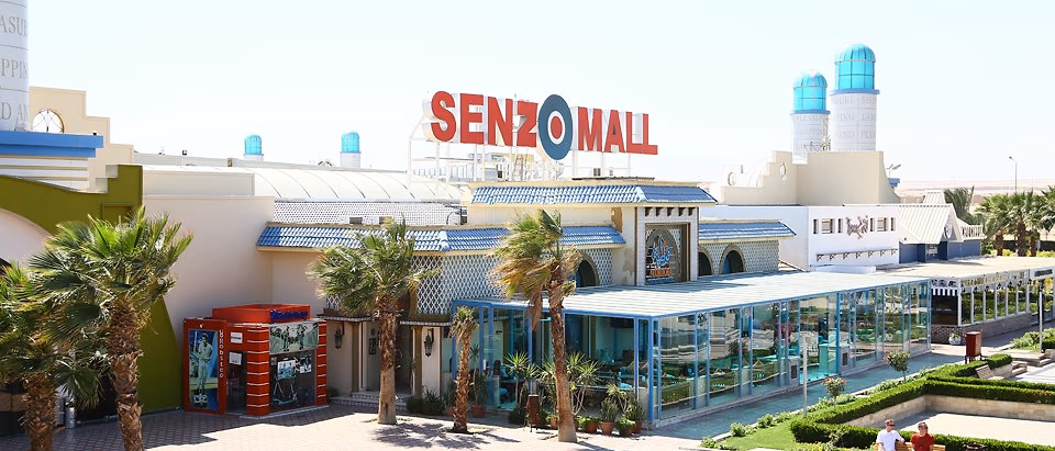 Buitengevel van Senzo Mall in Hurghada met het rode Senzo Mall-logo, palmbomen en een glazen paviljoen