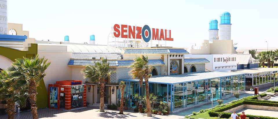 Senzo Mall in Hurghada van buiten, met het rode logo boven de ingang, palmbomen en een glazen paviljoen