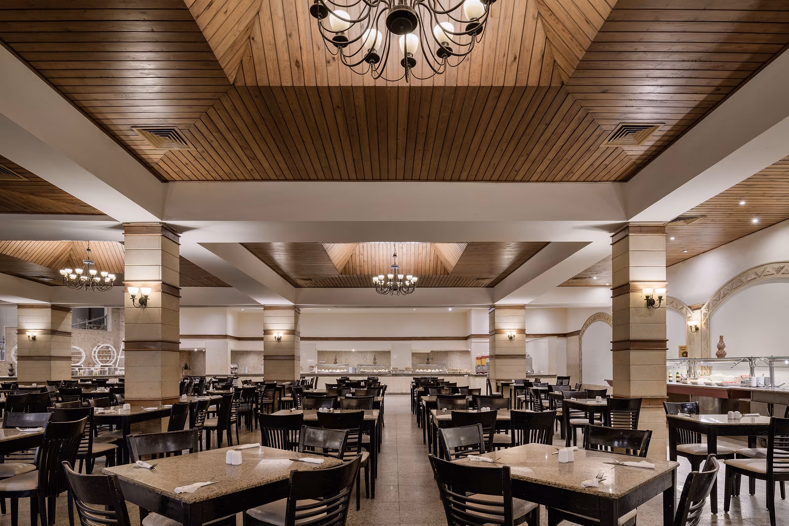 Grote buffetzaal met houten plafond, kroonluchters en donkere stoelen in Hotel Sindbad Club in Hurghada