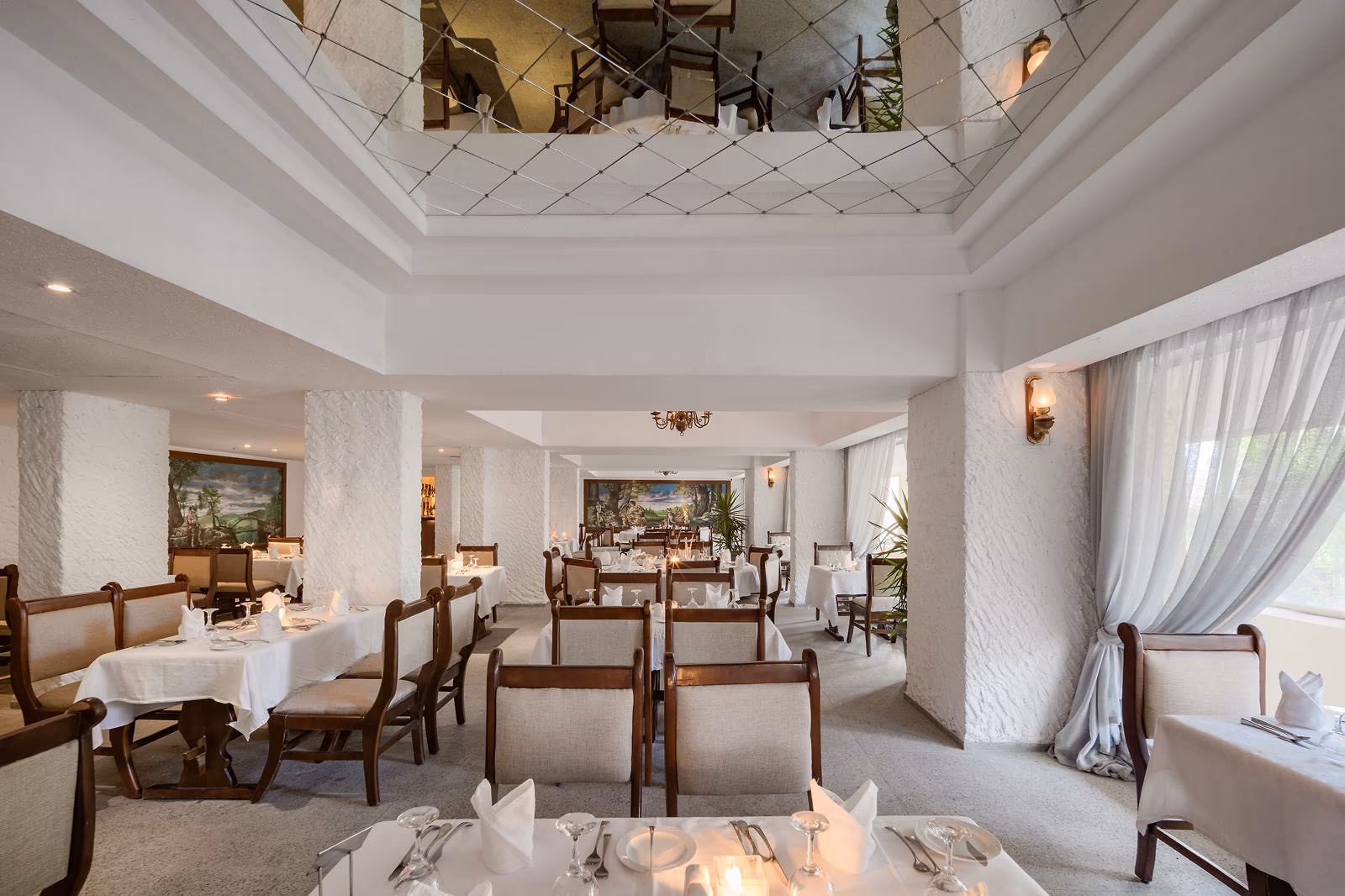 Restaurant met spiegelplafond, wandschilderingen en gedekte tafels in Hotel Sindbad Club in Hurghada