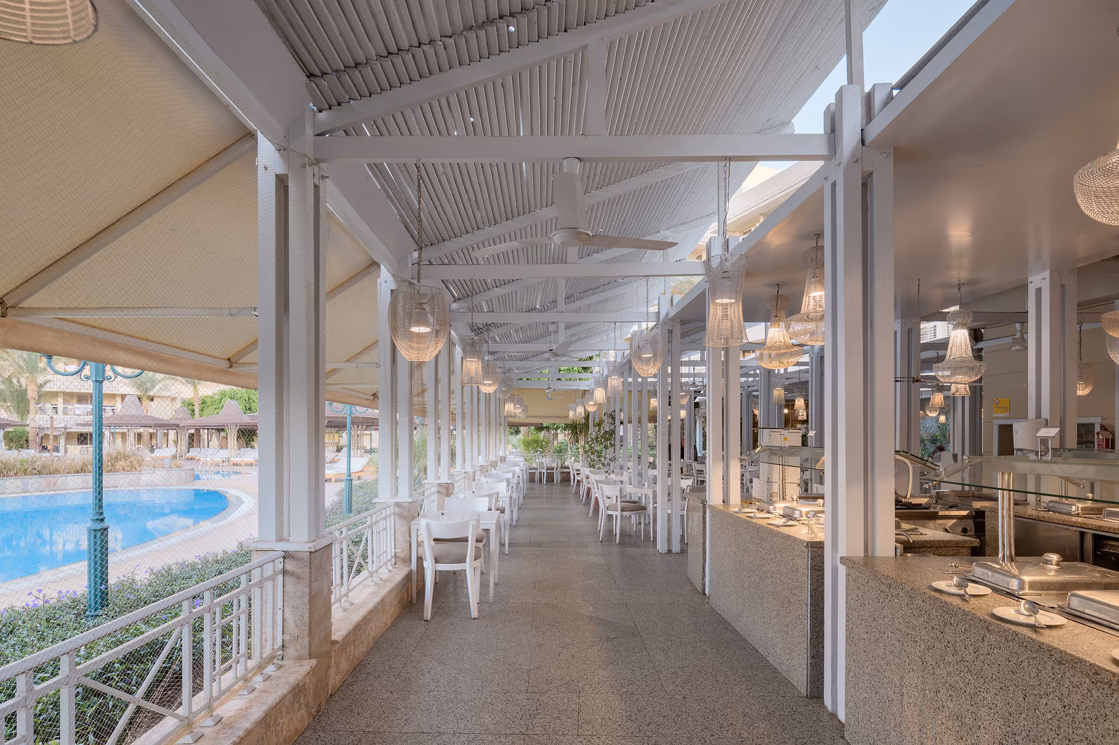 Overdekte buffetgang met witte tafels en zicht op het zwembad bij Hotel Sindbad Club in Hurghada