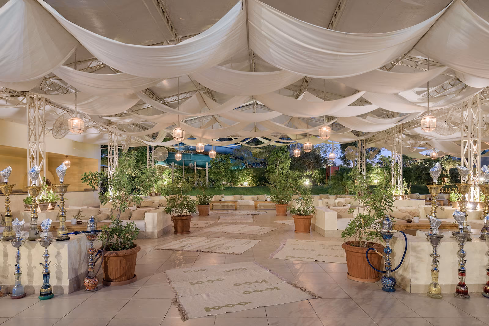 Lounge onder witte doeken met waterpijpen, kussens en planten bij Hotel Sindbad Club in Hurghada