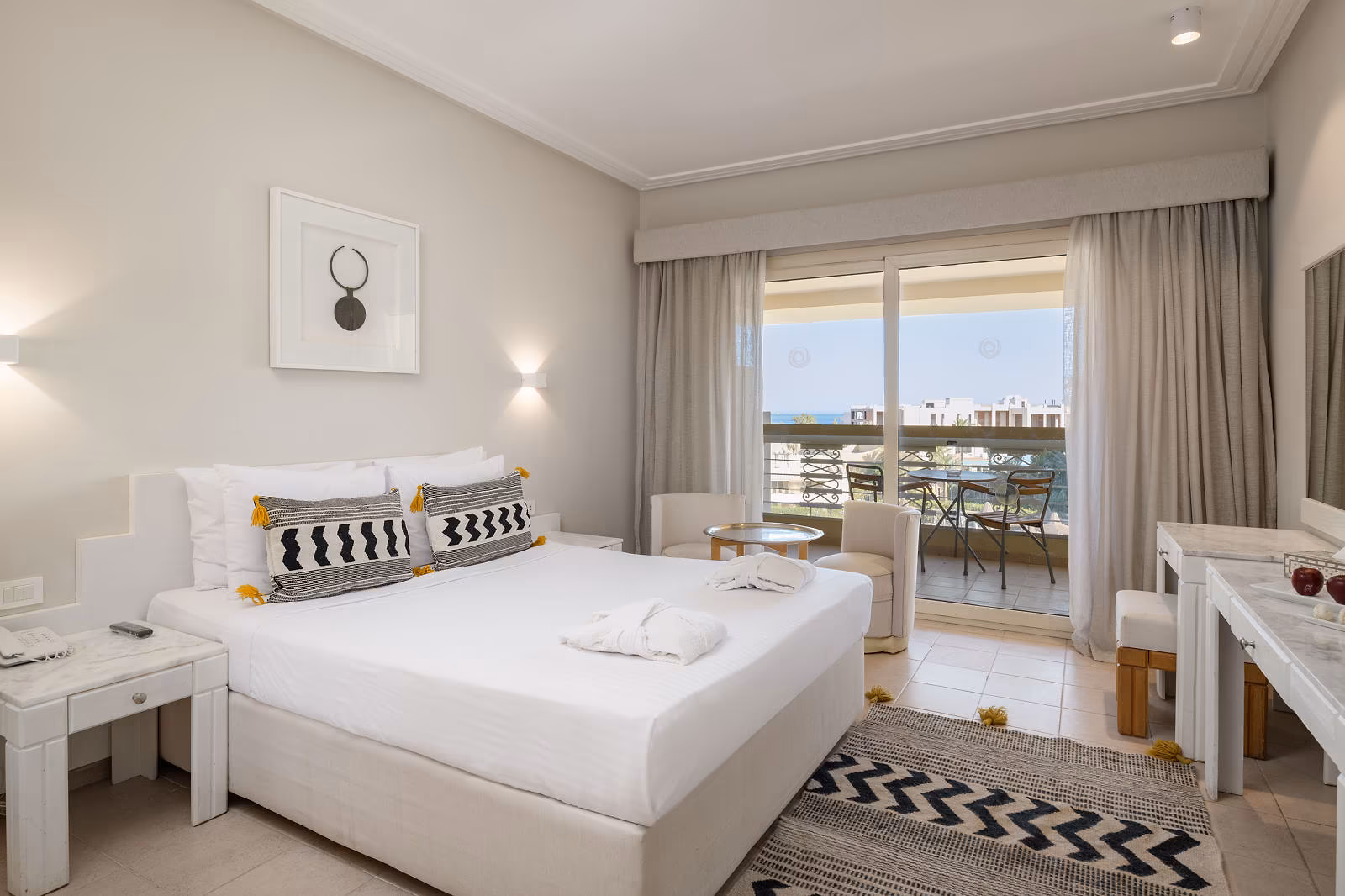 Superior kamer met kingsize bed, zwart-wit sierkussens en een balkon met zitje in Hotel Sindbad Club in Hurghada