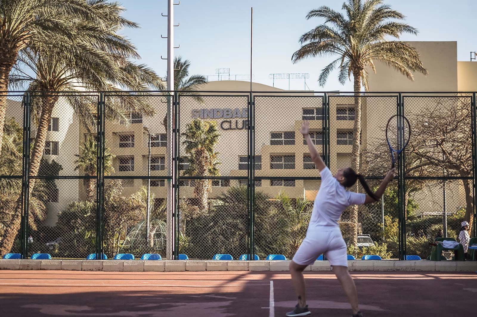 Tennisser serveert op een baan met het Sindbad Club-logo op het hotelgebouw erachter in Hurghada