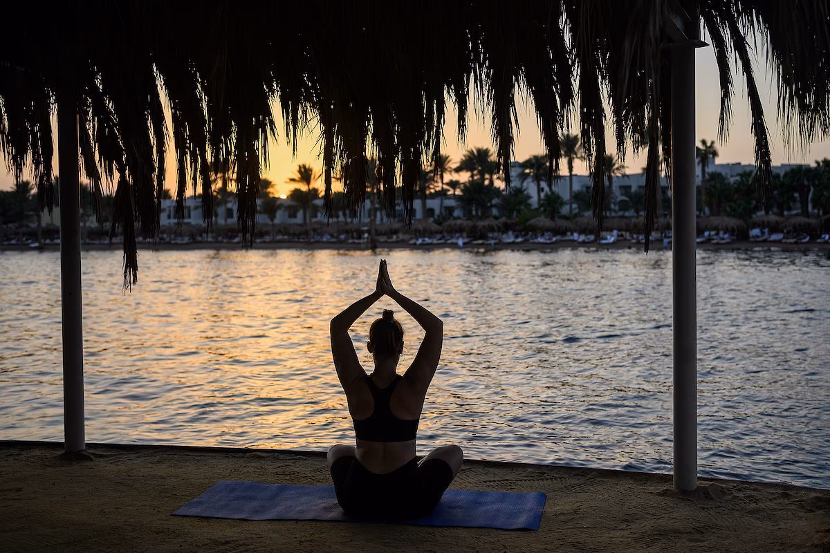 Yoga bij zonsopkomst onder een rieten afdak aan het water bij Hotel Sindbad Club in Hurghada