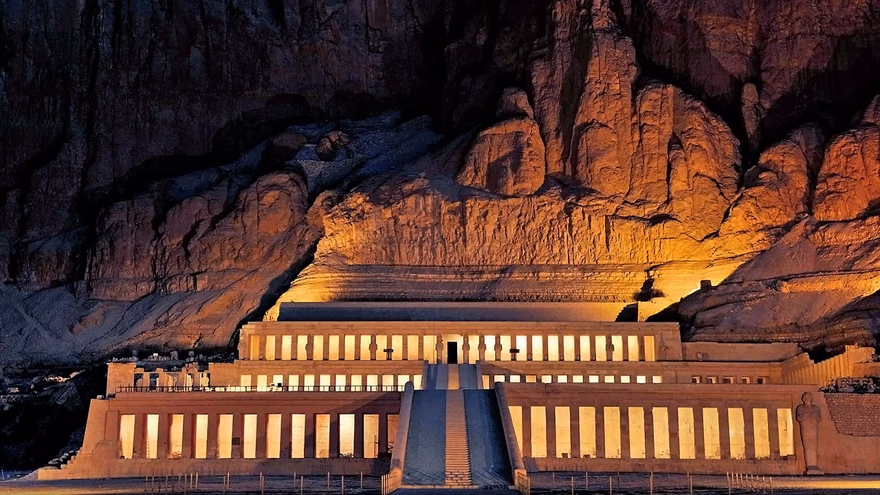 De verlichte tempel van Hatshepsut bij Luxor tegen de rotswand in de avond